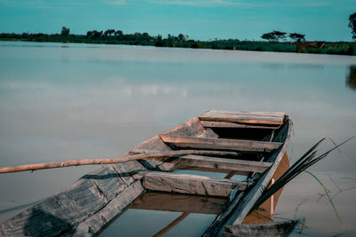 Wooden boat in lake against sky
