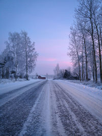 Road amidst bare trees against sky during winter