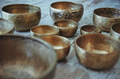 Assorted round shaped singing bowls with spots on metal surface on rough floor on blurred background