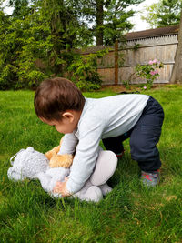 Young child picking up stuffed animals outdoors