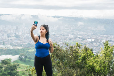 Young woman. latin influencer taking a selfie for her social networks on top of a mountain