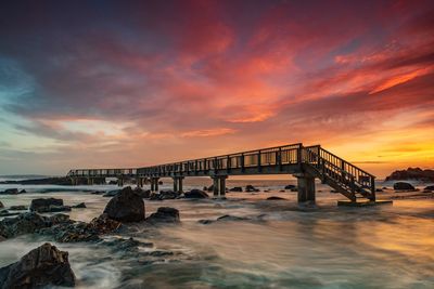 Bridge over sea against sky during sunset