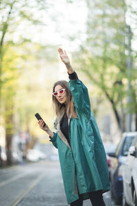 Young woman using mobile phone while standing on road