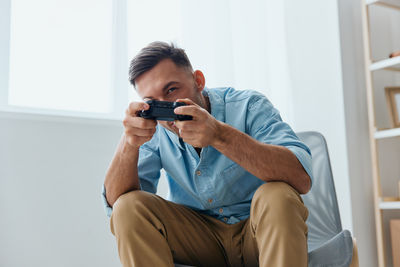 Young man using phone while sitting on sofa at home