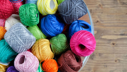 Directly above view of colorful thread balls in container on table