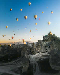 Hot air balloons flying over sea against sky during sunset