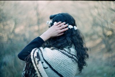 Side view of woman wearing flower tiara with blanket in forest