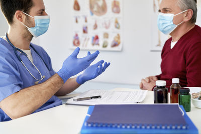 Doctor wearing mask consulting patient in clinic