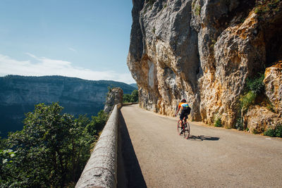 Scenic view a cyclist on a mountain road. rear view of man riding bicycle on mountain road. 