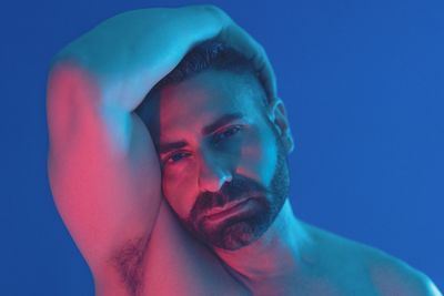 Close-up portrait of young man against blue background