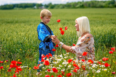 Side view of mother and son by plants on field