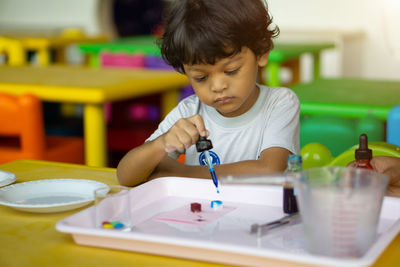 Boy holding dropper while painting toy