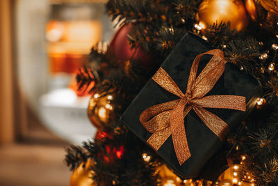 Velvet new year's gift with a gold ribbon hanging on the christmas tree. 