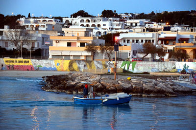 Boats in sea against buildings in city