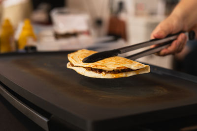 Chef preparing fresh quesadilla on black grill at local food market.