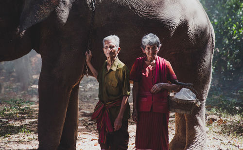 Senior couple standing by elephant in forest