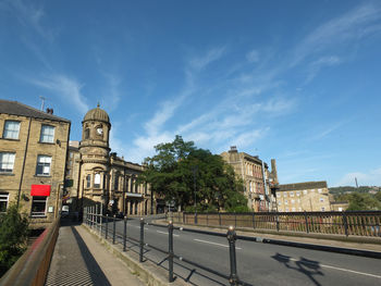 Street by buildings against blue sky