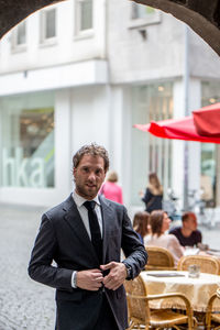 Portrait of businessman standing on footpath in city