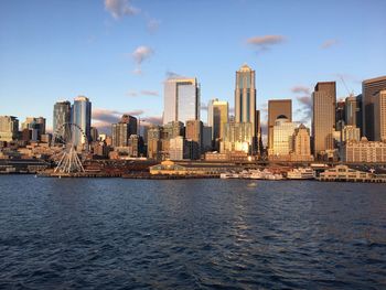 Sea by modern buildings in city against sky