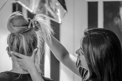 Hairdresser tying hair of woman