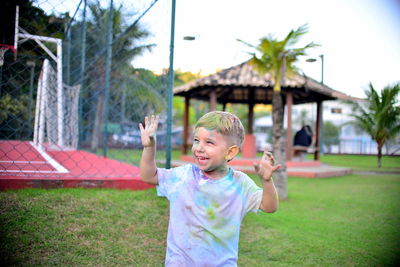 Cheerful boy covered with colorful powder pain standing at park