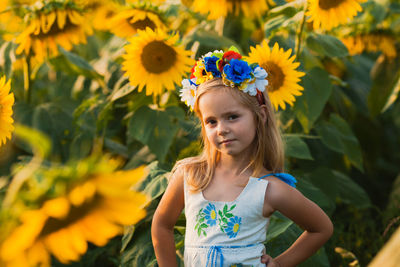 Portrait of cute girl standing on yellow flowering plants