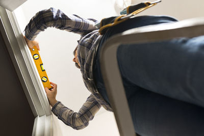 Low angle view of woman measuring wall