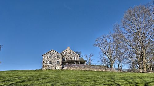 House on field against clear blue sky