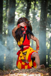 Side view of young woman standing in forest