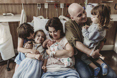 Mid view of whole family holding newborn son in hospital