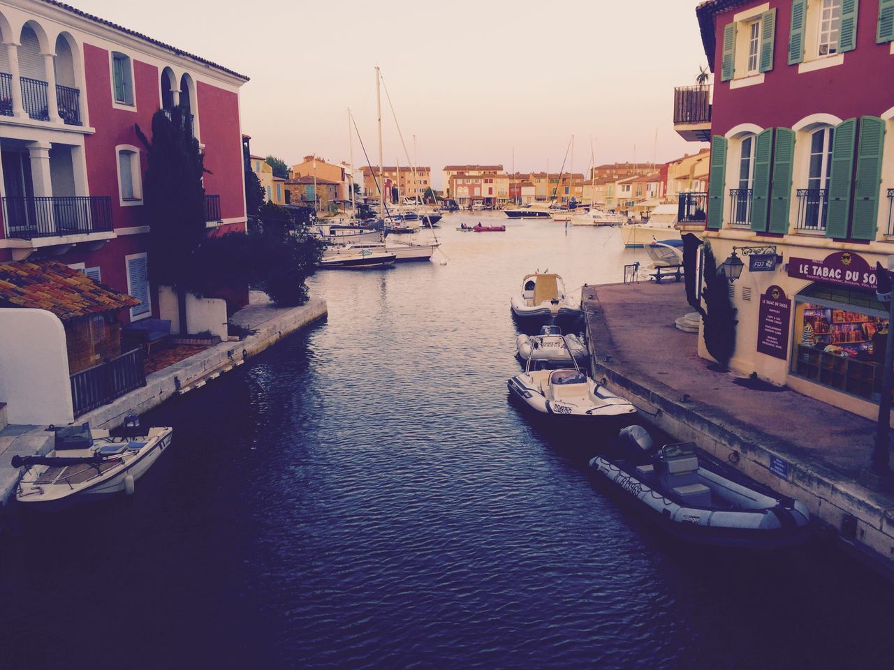 BOATS MOORED AT HARBOR AGAINST SKY IN CITY