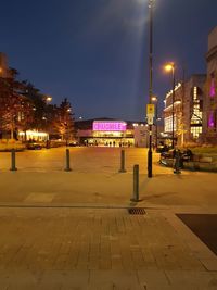 Illuminated street amidst buildings in city at night
