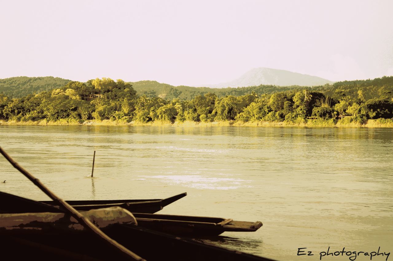 water, tranquil scene, tranquility, lake, tree, mountain, scenics, nature, beauty in nature, boat, wood - material, day, calm, non-urban scene, idyllic, lakeshore, outdoors, no people, non urban scene, mountain range, sky, remote, landscape, rippled, growth