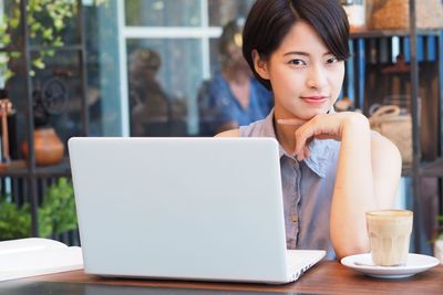 Portrait of young woman using smart phone in cafe