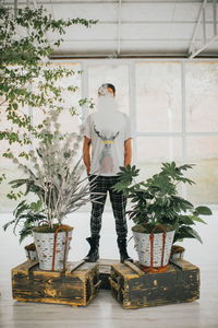 Young man standing by potted plant