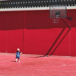 Full length of man standing against red wall