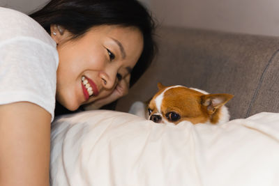 Pet owner looking at chihuahua dog while lying on a bed