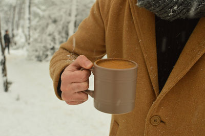 Midsection of man holding coffee cup during winter