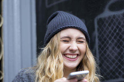Portrait of laughing young woman with smartphone
