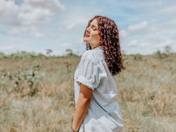 Side view of young woman standing on field