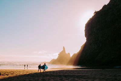 People on beach against sky during sunset