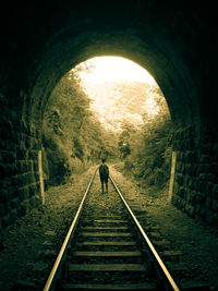 Rear view of man walking on railroad track