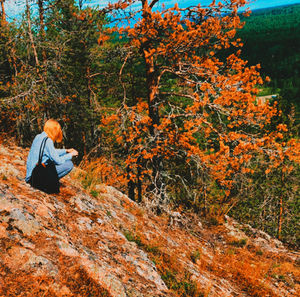 Rear view of woman sitting on rock