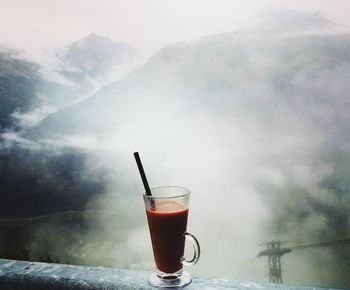 Close-up of drink on glass against mountain