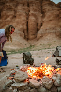 Camper sets up her chair to read next to fire in utah desert