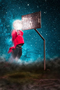 Optical illusion of man dunking moon in basketball hoop against sky