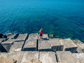 High angle view of boy fishing on sea shore