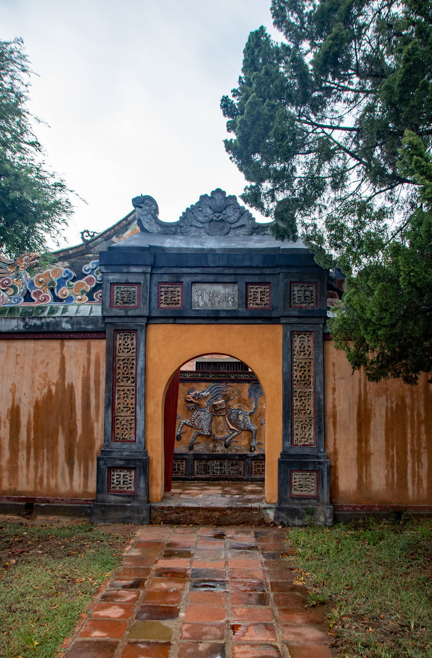 tree, architecture, plant, built structure, building exterior, sky, nature, day, no people, entrance, the past, history, gate, cloud - sky, outdoors, art and craft, park, arch, communication, travel destinations