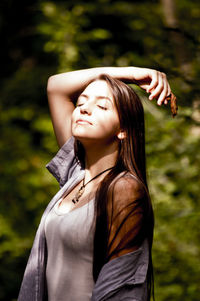 Young woman looking away while standing against plants