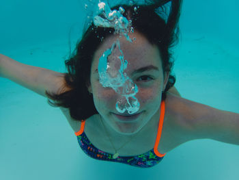 Close-up portrait of young woman swimming underwater